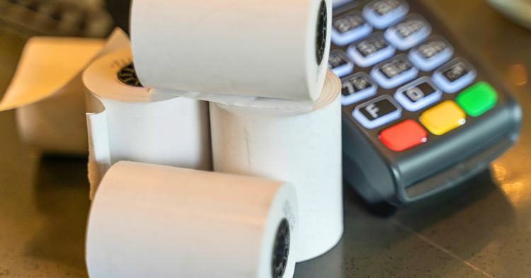 Stacks of receipt paper containing BPA sit in from of credit card processing machine.