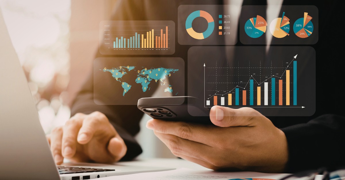 image: torso and hands of person using a laptop and holding a smart phone as data insights pop up in 3D from the mobile device
